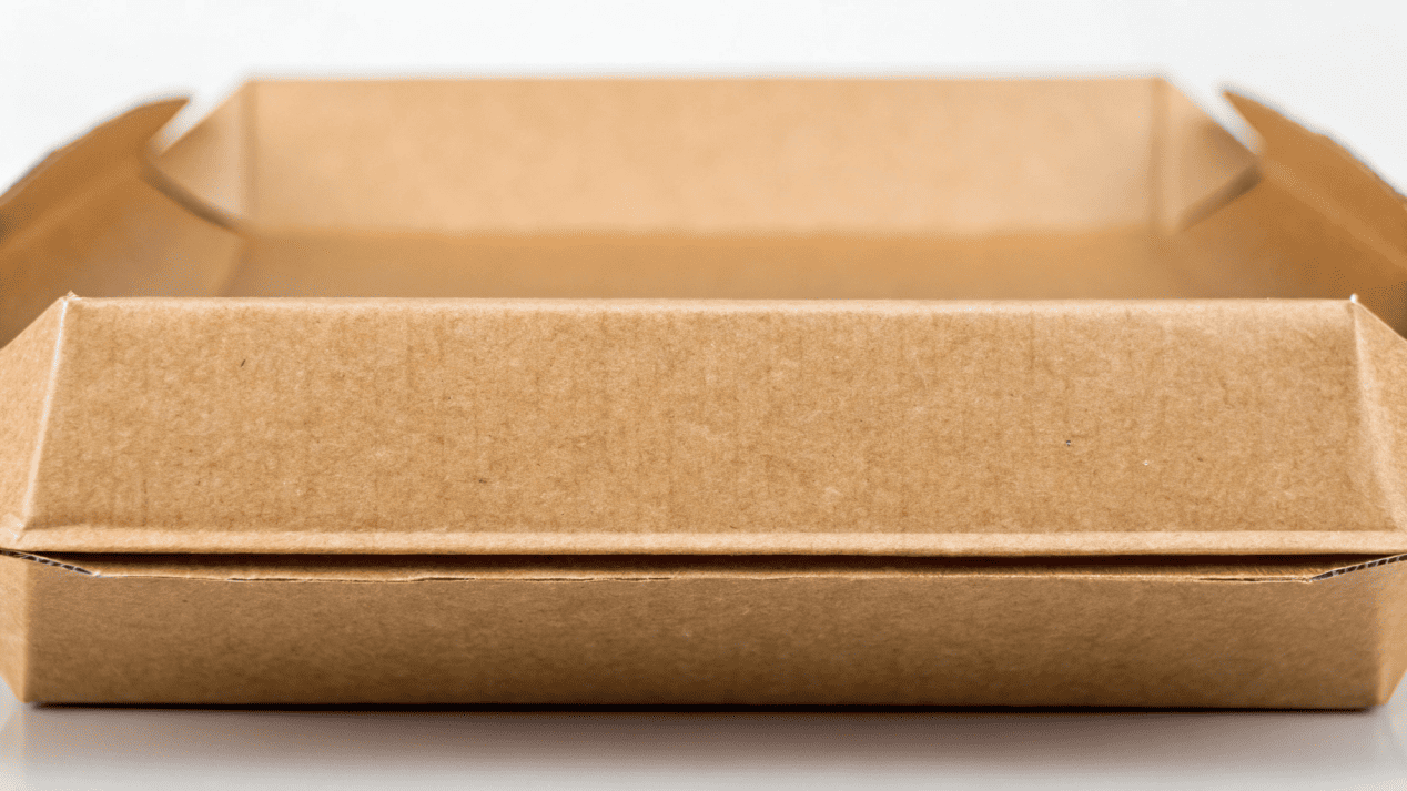 A close-up cross-section of a paperboard box showing the inner grease-resistant PLA lining
