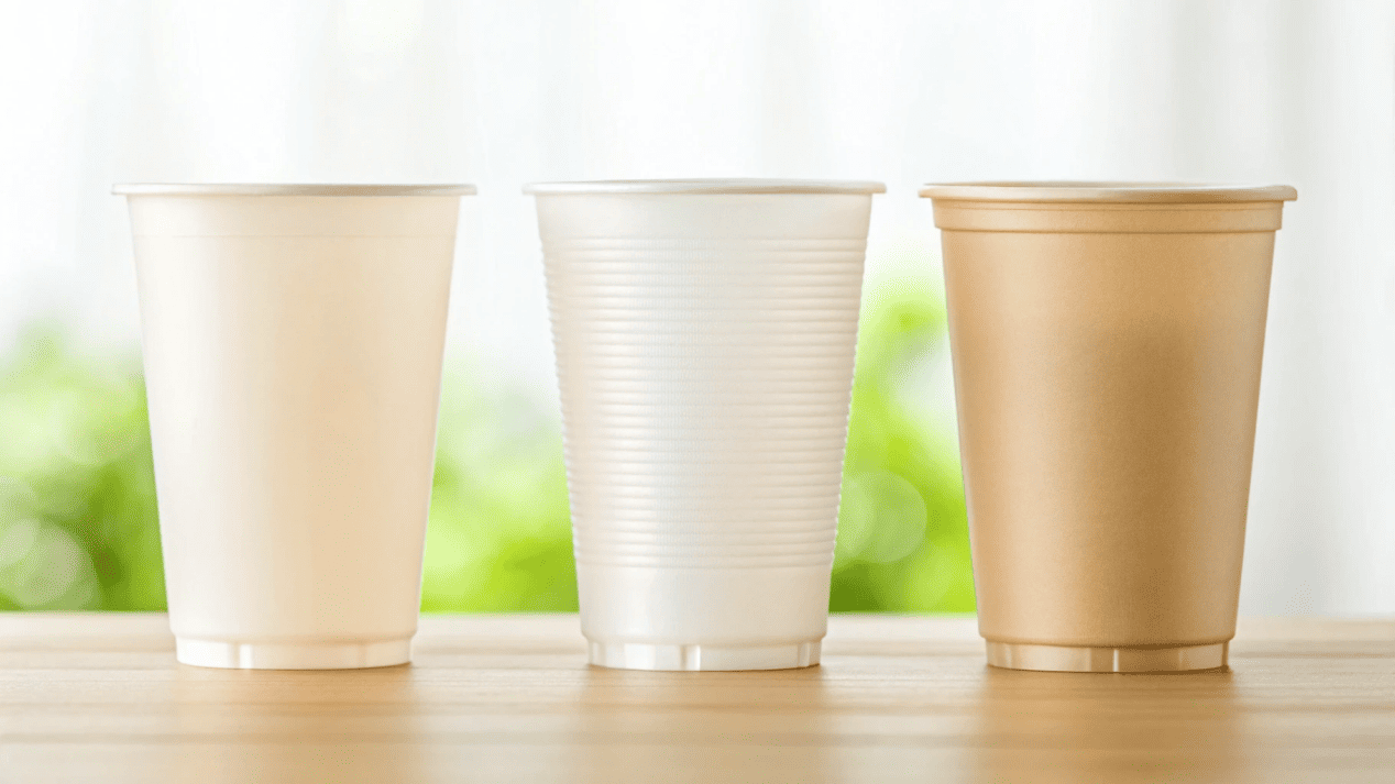 A lineup of different disposable cups: paper, clear plastic, and bagasse