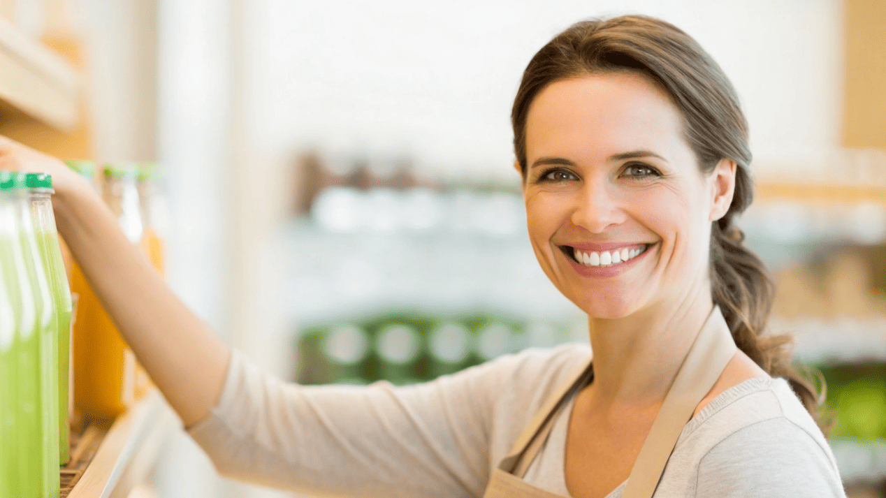 A customer smiling as they choose a product from a brand that uses clearly marked compostable packaging.