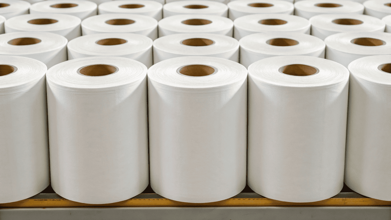 Raw Material Sourcing for Paper Bowls Rolls of raw, food-grade paperboard waiting to be used in production.