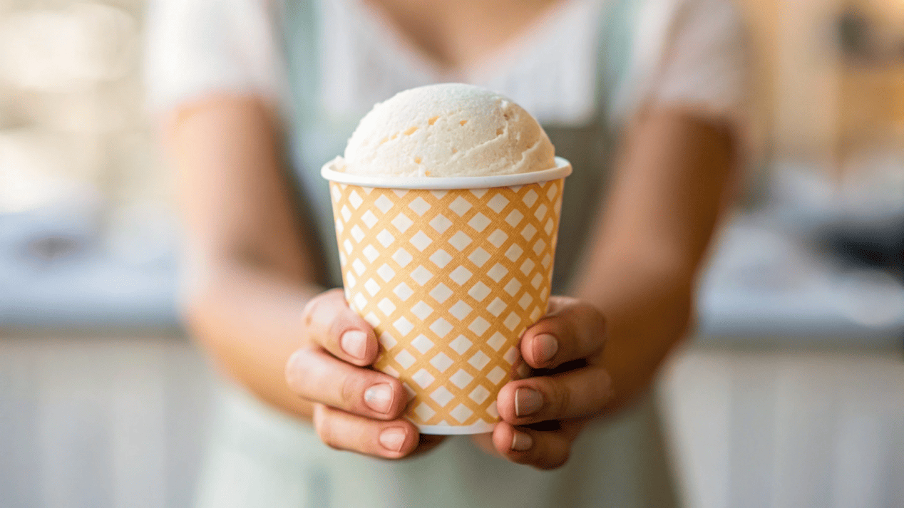 A customer holding a beautifully designed custom printed ice cream cup with the shop's logo
