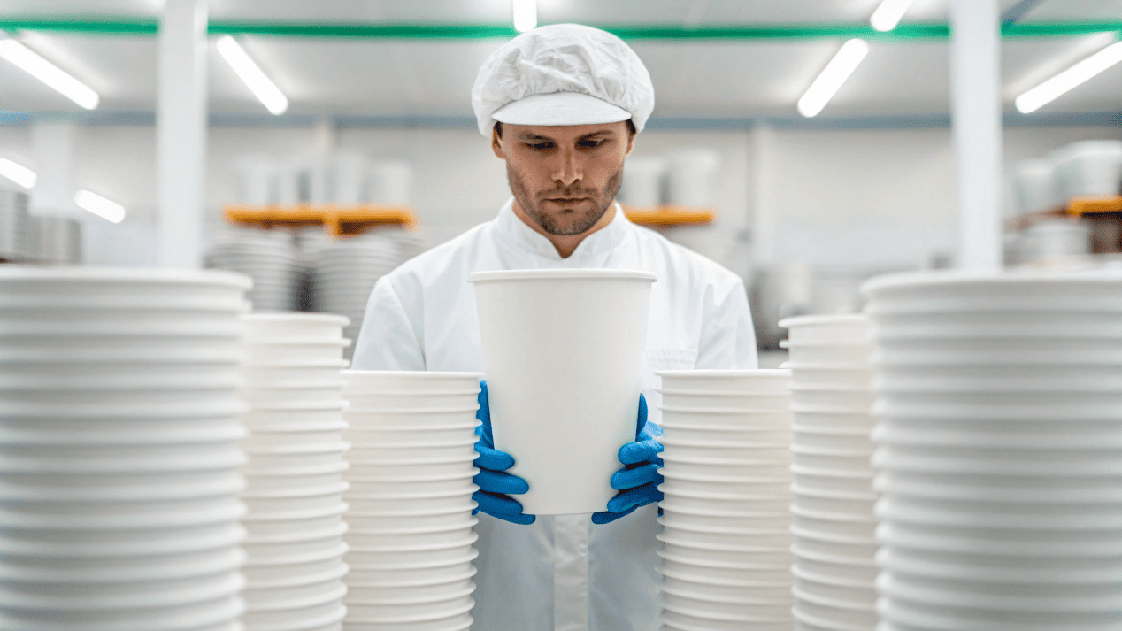 A factory worker inspecting a freshly printed large capacity ice cream cup for quality control