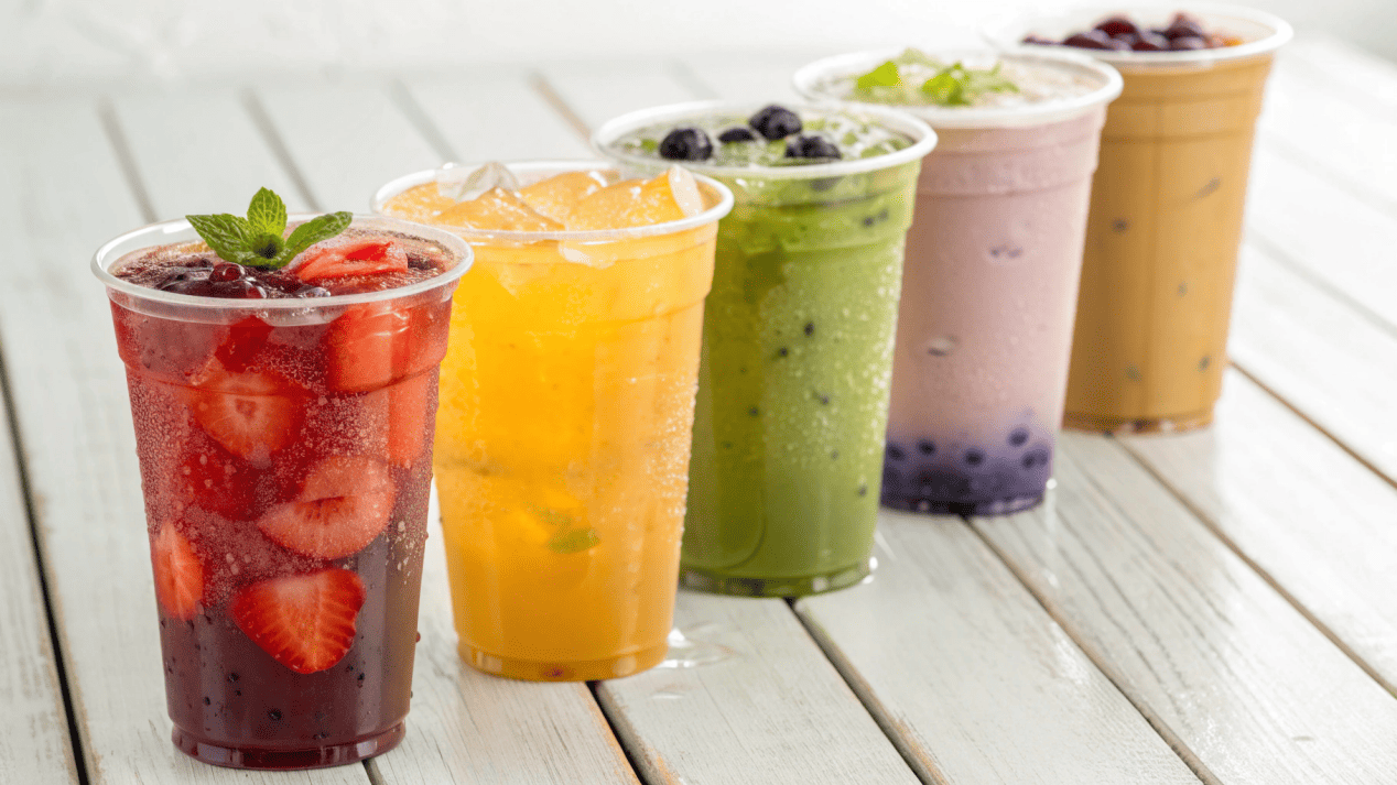 Enhancing Drink Aesthetics with PLA Cups A row of vibrant smoothies and iced coffees in branded PLA cups.