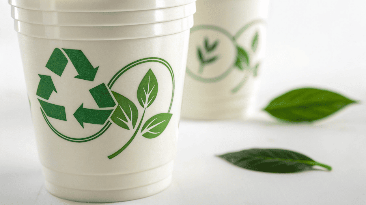 A PLA cup showing the BPI compostable certification logo next to the EN 13432 logo