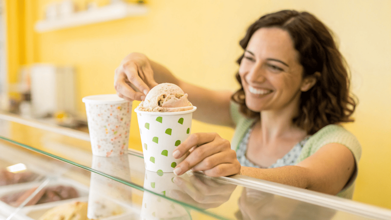 A customer smiling as they choose an ice cream in a branded paper cup over a generic plastic one.