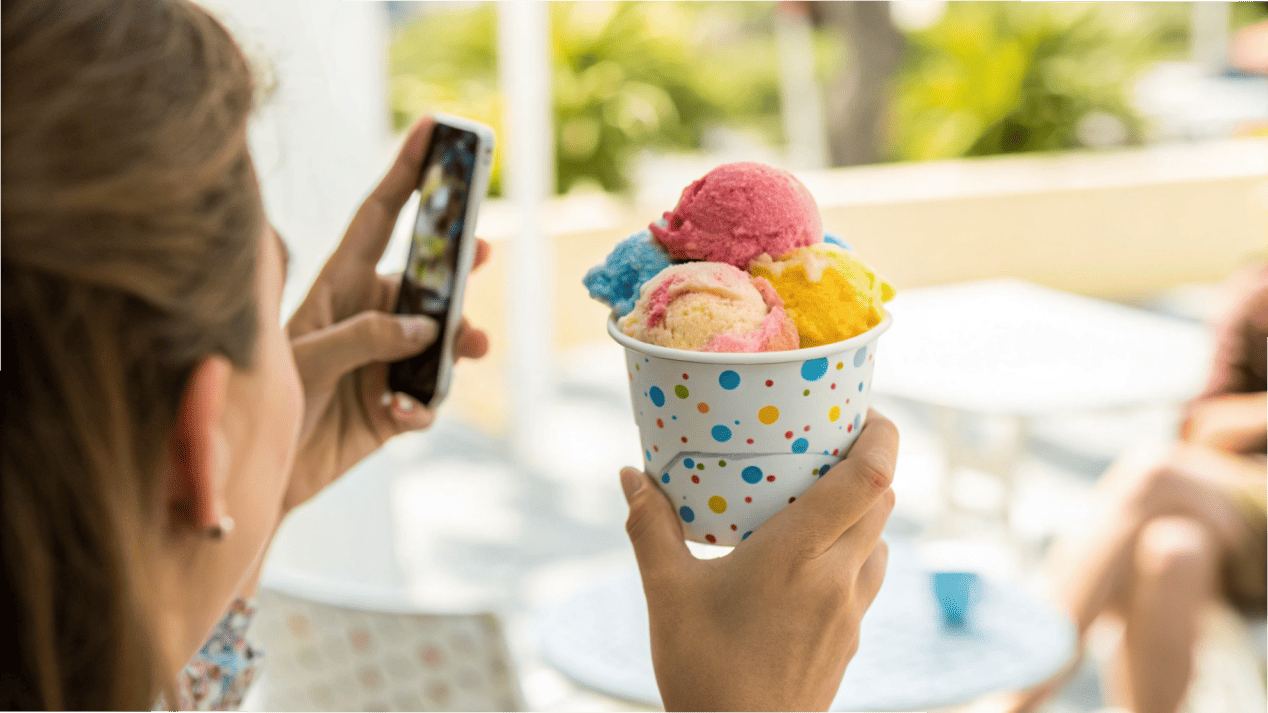 Instagrammable Custom Ice Cream Cups A person taking a photo of a colorful, branded ice cream cup for Instagram.