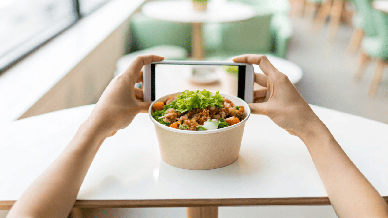 A person taking a photo of their food in a beautifully branded bowl for social media.