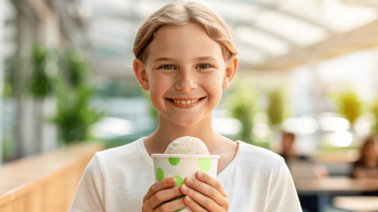 A happy young customer enjoying ice cream from a stylish, branded, eco-friendly cup.