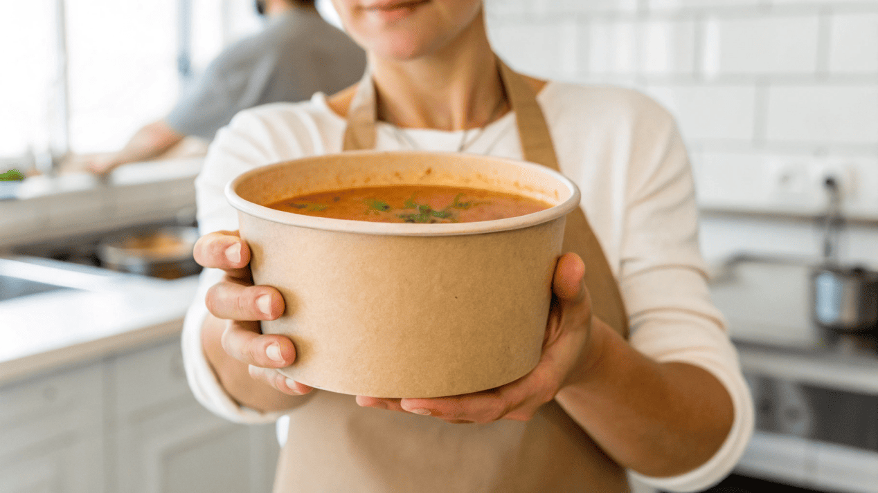 A person confidently holding a sturdy paper soup bowl that maintains its shape.
