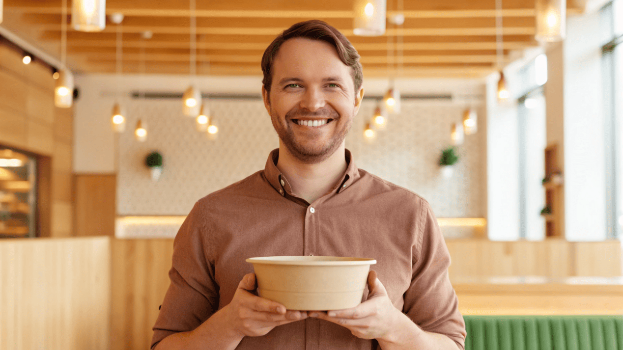 A customer smiling as they read the safety information on a paper bowl.