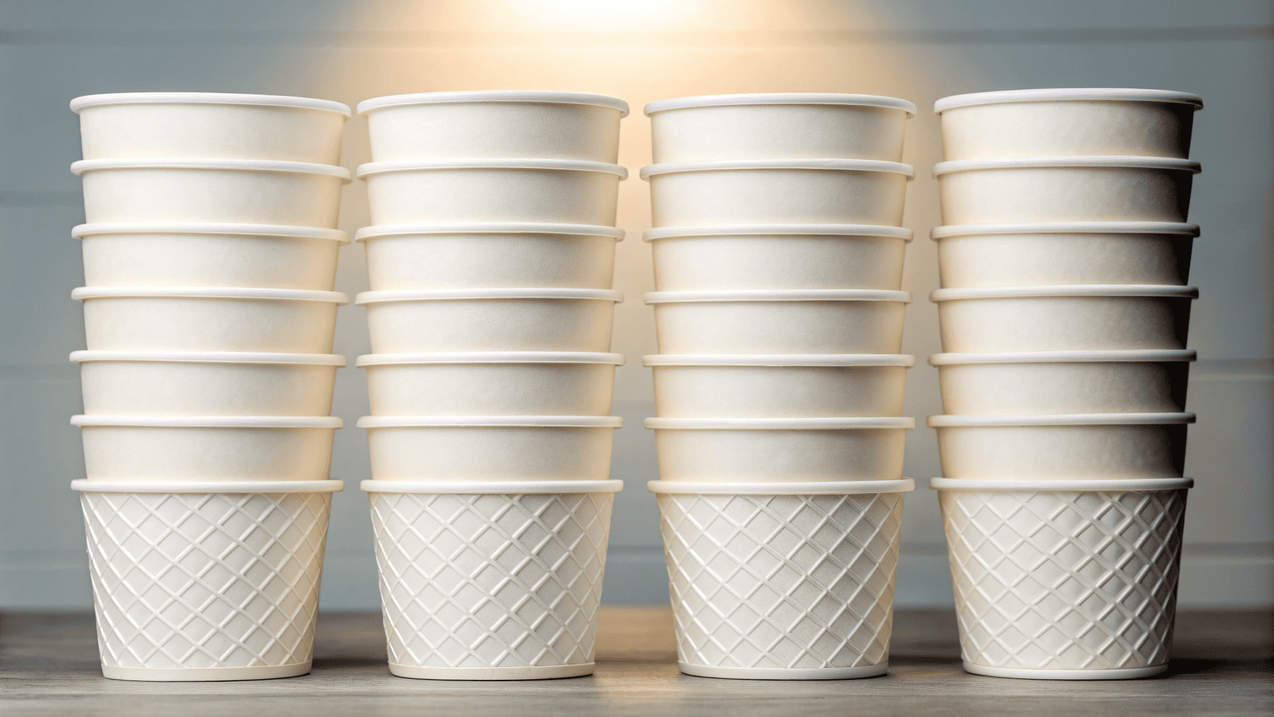A stack of different sized ice cream cups that all share the same diameter, showing they can use one lid.