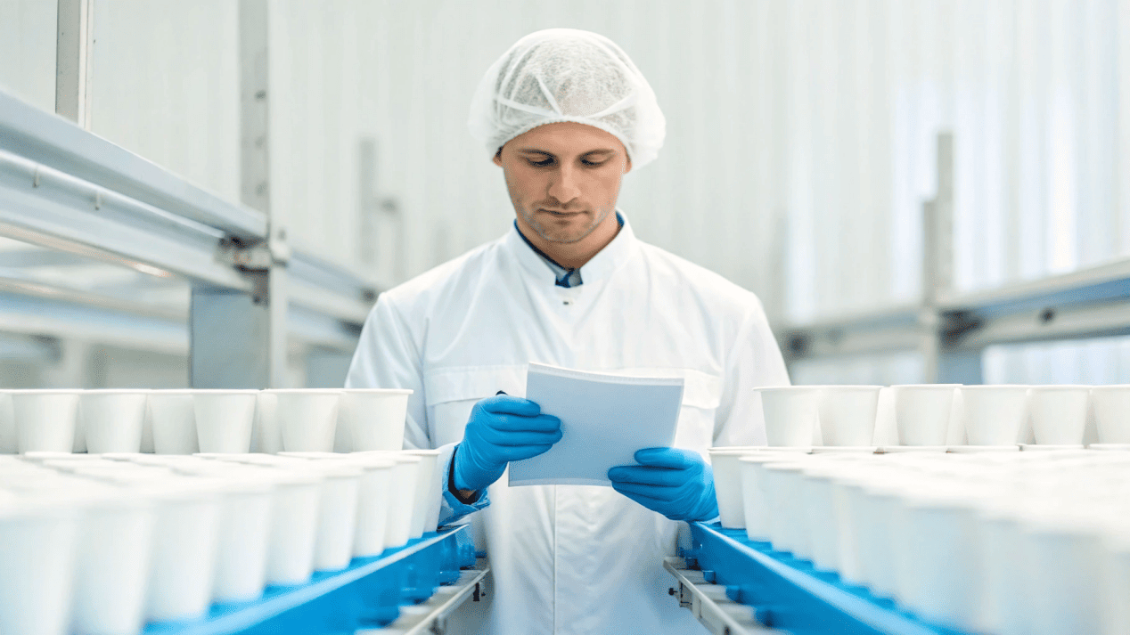 Global Quality Assurance for Paper Cups A quality control inspector examining paper cups on a production line.