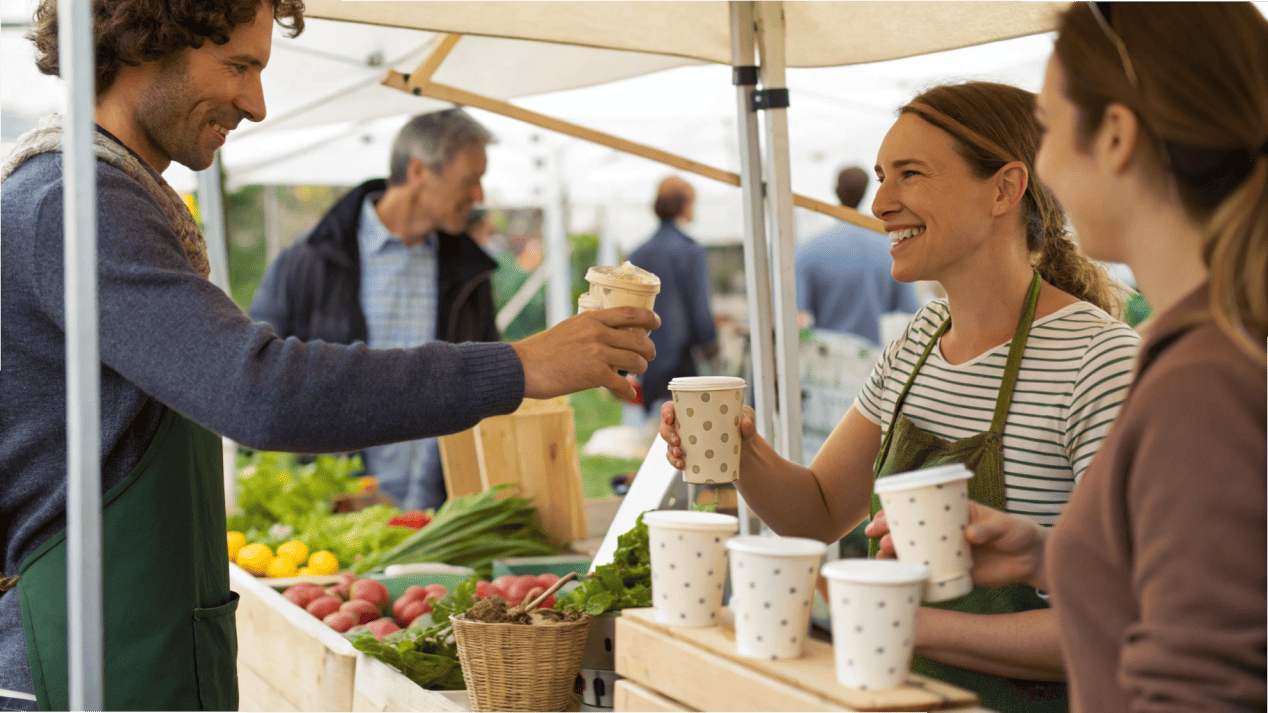 A friendly pop-up ice cream stall at a local farmers market with branded cups.