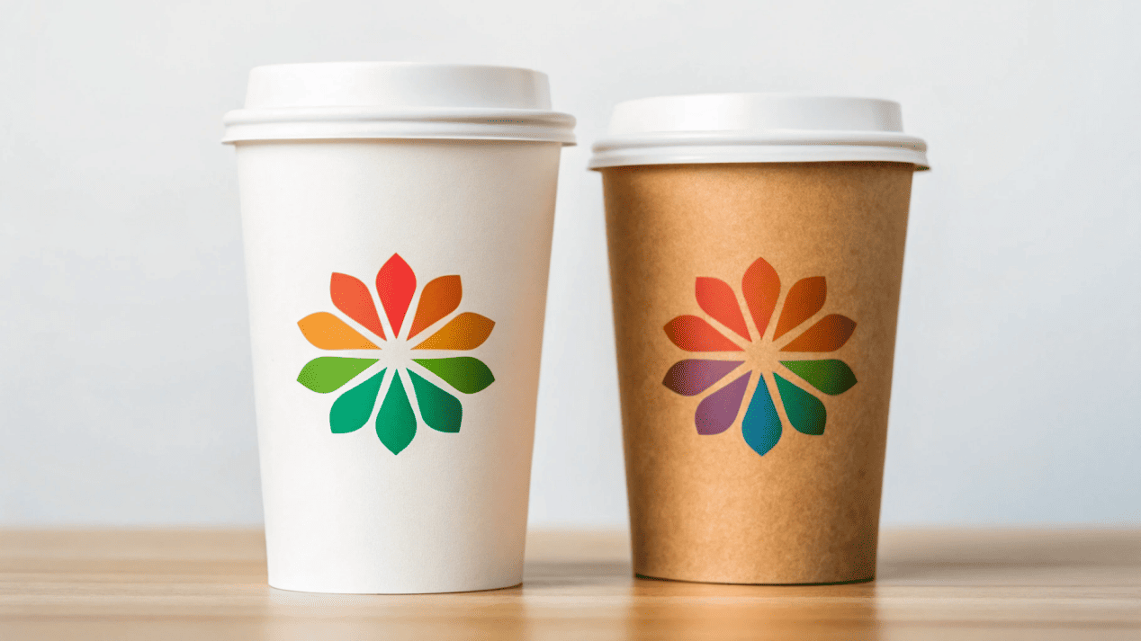 A vibrant, colorful logo on a white cup next to the same logo looking earthy on a Kraft cup.